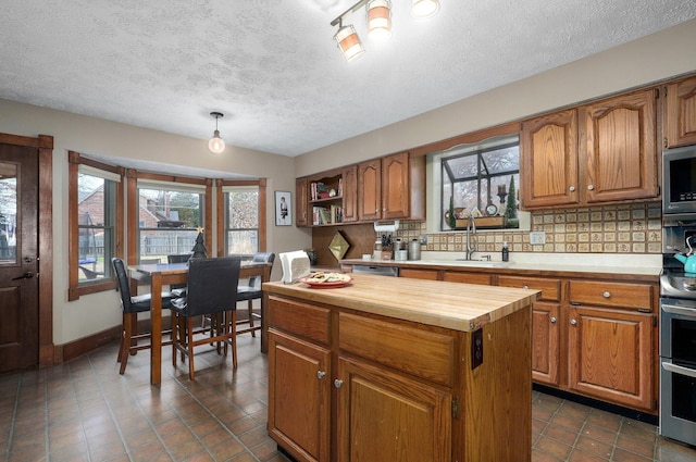 kitchen featuring plenty of natural light, butcher block counters, decorative backsplash, and stainless steel appliances