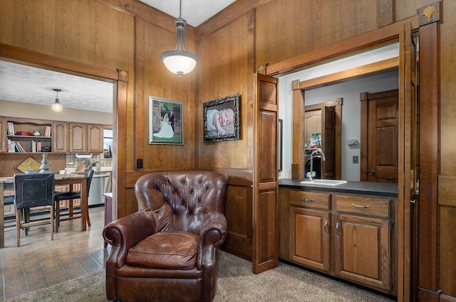 sitting room with carpet flooring, a textured ceiling, wood walls, and sink