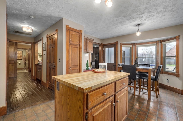 kitchen with butcher block countertops, a center island, dark wood-type flooring, and a textured ceiling