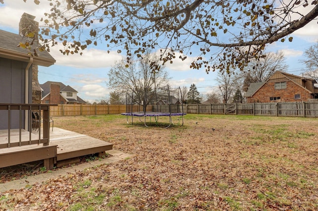 view of yard featuring a trampoline and a wooden deck