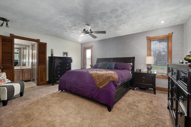 carpeted bedroom featuring multiple windows, a textured ceiling, ceiling fan, and connected bathroom