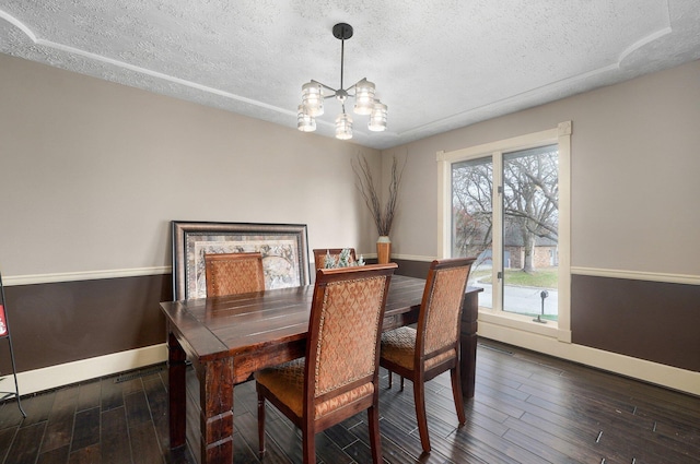 dining space with a textured ceiling, dark hardwood / wood-style floors, and an inviting chandelier