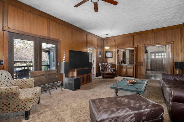 living room with a textured ceiling, ceiling fan, and wooden walls