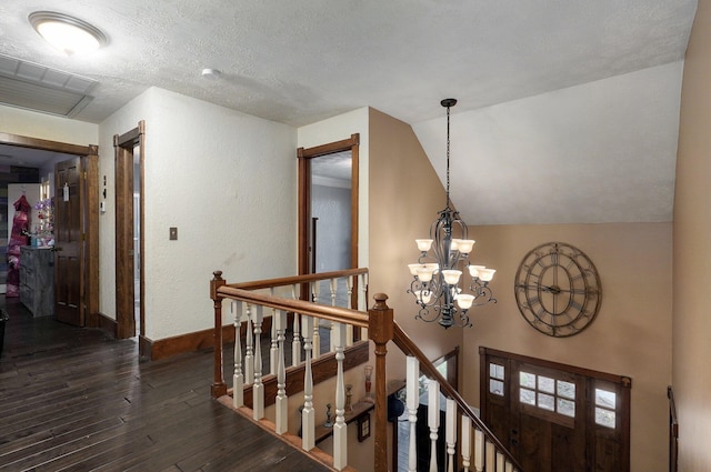 corridor with dark hardwood / wood-style flooring, lofted ceiling, a textured ceiling, and an inviting chandelier