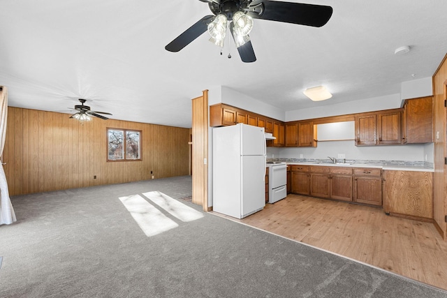 kitchen with white appliances, ventilation hood, sink, wooden walls, and light wood-type flooring