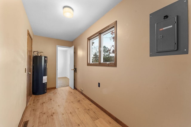 corridor with light hardwood / wood-style floors, electric water heater, and electric panel