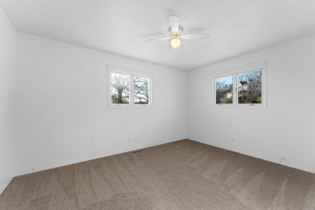 carpeted spare room featuring ceiling fan and a healthy amount of sunlight