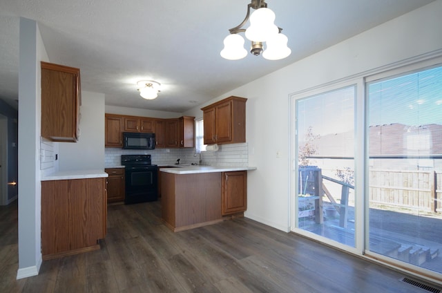 kitchen featuring decorative light fixtures, an inviting chandelier, dark wood-type flooring, and black appliances