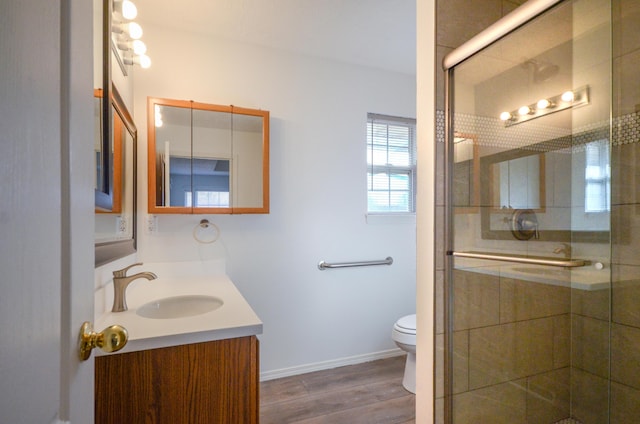 bathroom featuring hardwood / wood-style flooring, vanity, toilet, and a shower with shower door