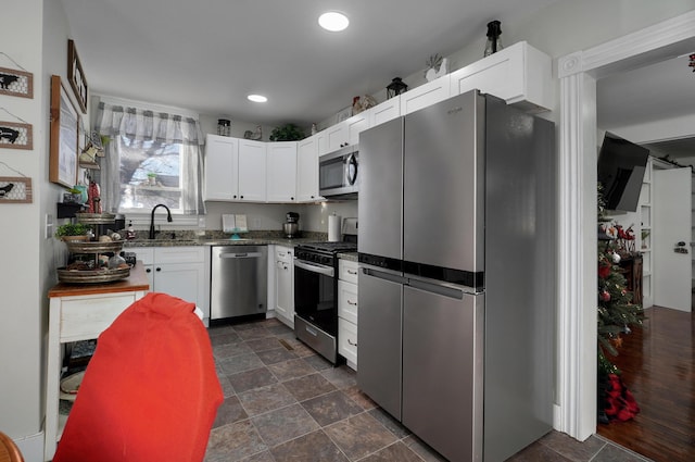 kitchen featuring white cabinetry, sink, appliances with stainless steel finishes, and dark stone counters