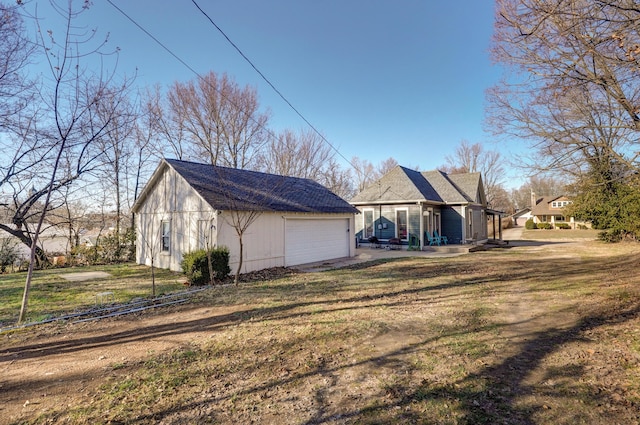 view of side of property featuring a garage, a yard, and an outbuilding