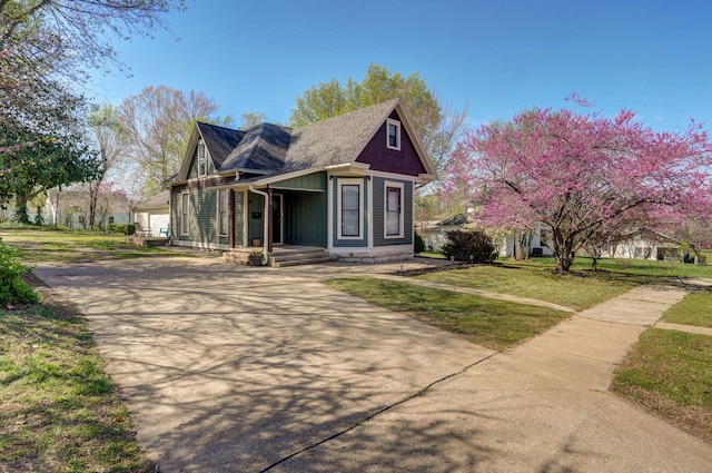 victorian home with concrete driveway and a front lawn