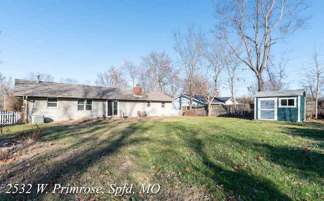 rear view of property with central AC, a storage shed, and a lawn