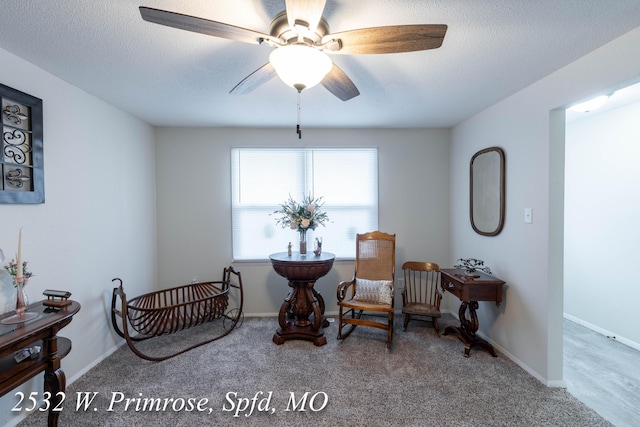 sitting room with carpet, ceiling fan, and a textured ceiling