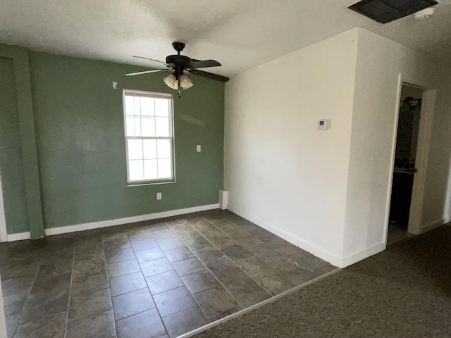 unfurnished room with ceiling fan and dark tile patterned flooring