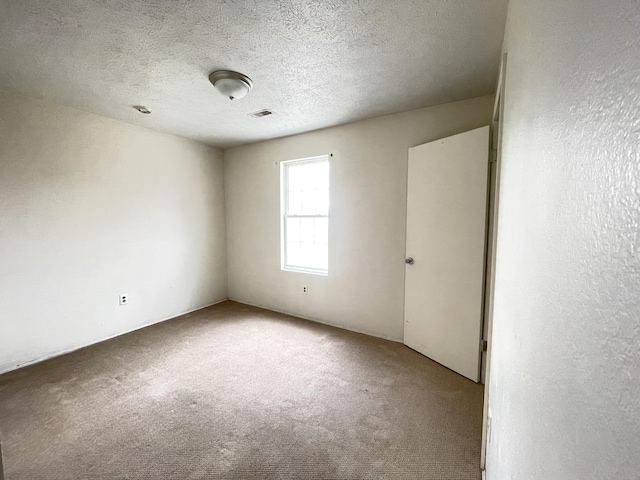 carpeted spare room featuring a textured ceiling