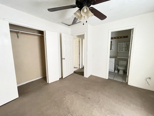 unfurnished bedroom featuring dark colored carpet, ensuite bathroom, ceiling fan, and a closet