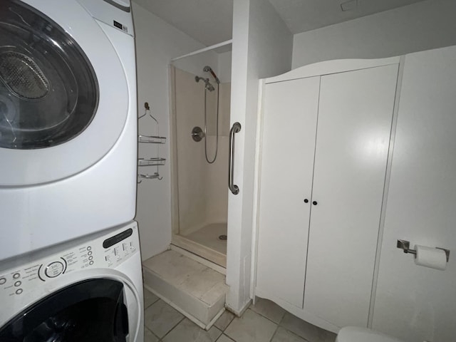 laundry room featuring light tile patterned floors and stacked washer / drying machine