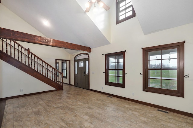 foyer entrance featuring ceiling fan, high vaulted ceiling, wood finished floors, baseboards, and stairs