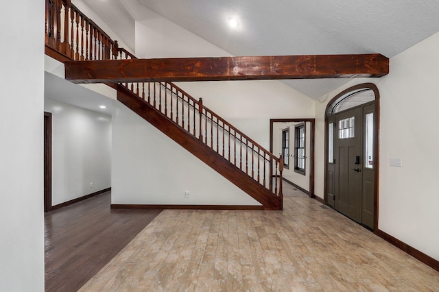 foyer with beam ceiling, stairway, wood finished floors, high vaulted ceiling, and baseboards