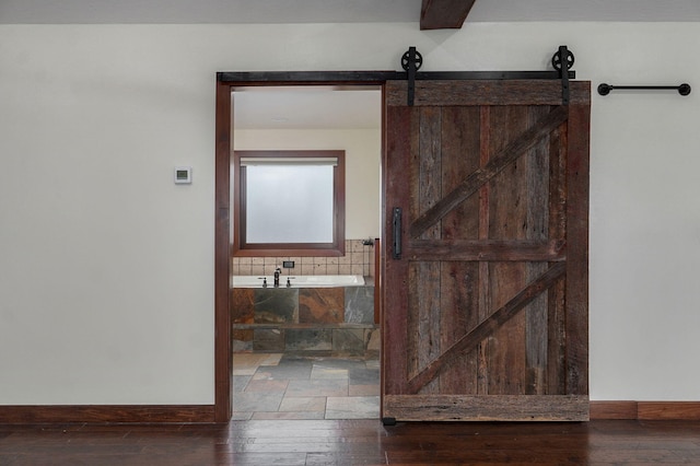 interior space featuring a tub to relax in, baseboards, and hardwood / wood-style flooring