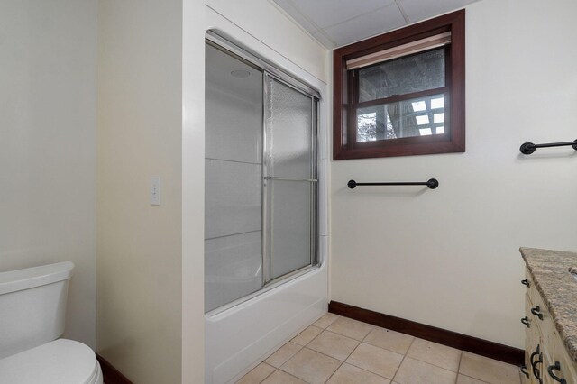 bathroom featuring baseboards, toilet, enclosed tub / shower combo, tile patterned flooring, and vanity