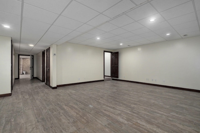 empty room featuring recessed lighting, a drop ceiling, wood finished floors, and baseboards