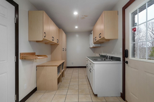 kitchen with a healthy amount of sunlight, baseboards, a sink, and light tile patterned flooring