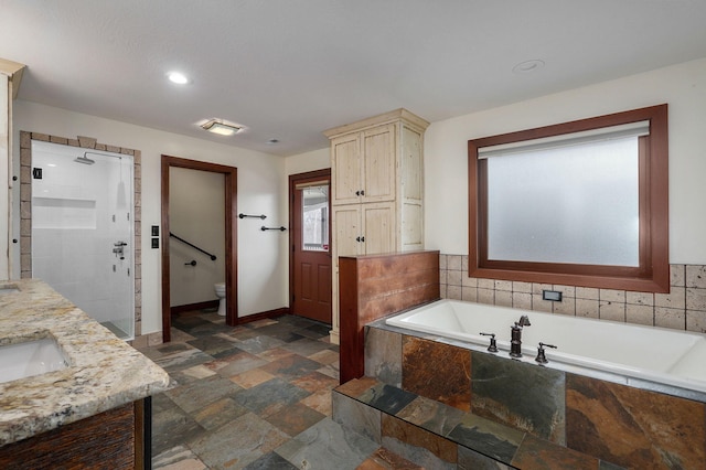 full bath featuring toilet, baseboards, a shower stall, a bath, and stone finish floor