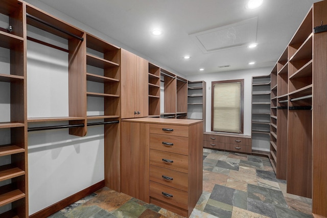 walk in closet featuring stone finish flooring and attic access