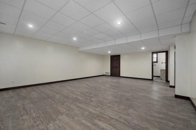 empty room featuring a paneled ceiling, visible vents, baseboards, and wood finished floors