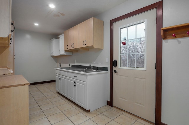 interior space featuring baseboards, light tile patterned flooring, a sink, and recessed lighting