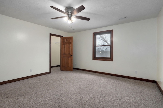 empty room featuring visible vents, light carpet, baseboards, and a textured ceiling