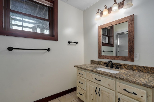 full bathroom featuring a shower with shower door, tile patterned flooring, vanity, and baseboards