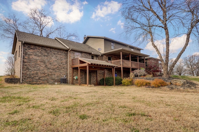 rear view of property featuring a deck, central AC, brick siding, and a lawn