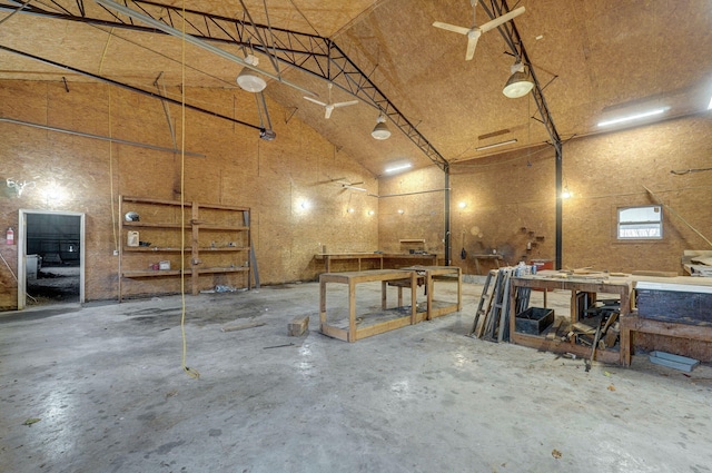 misc room with high vaulted ceiling, unfinished concrete floors, a garage, and a workshop area