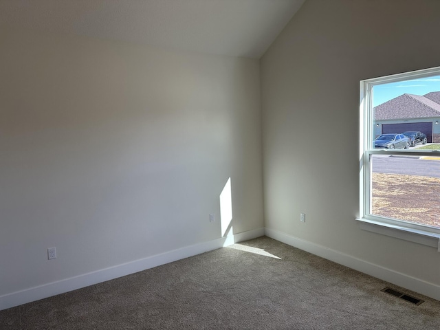 carpeted empty room with lofted ceiling