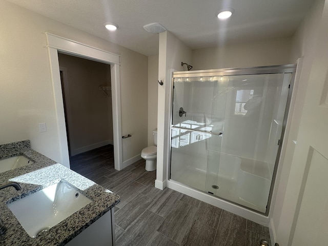 bathroom with hardwood / wood-style floors, vanity, toilet, and a shower with door