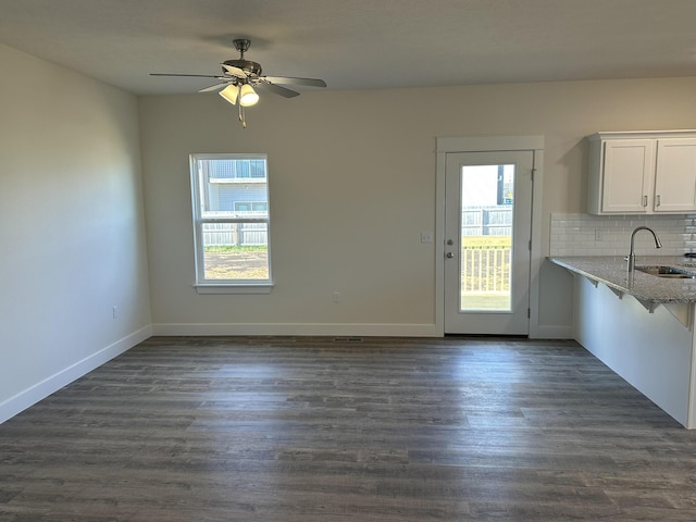 unfurnished dining area with dark hardwood / wood-style flooring, ceiling fan, and sink