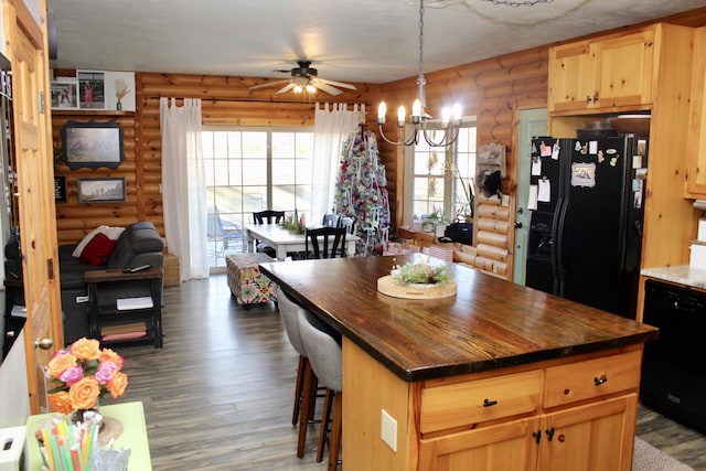 kitchen with rustic walls, a wealth of natural light, dark hardwood / wood-style flooring, and black appliances