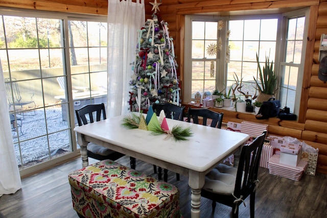 dining area featuring a healthy amount of sunlight, log walls, and wood-type flooring