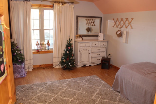 bedroom with light wood-type flooring and vaulted ceiling