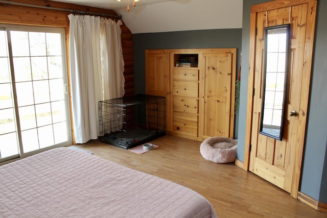 bedroom featuring wood-type flooring, a wood stove, multiple windows, and lofted ceiling