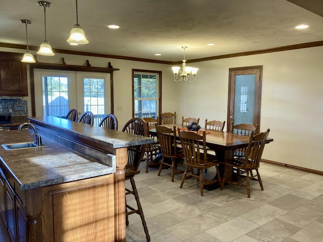 dining space featuring ornamental molding, sink, and a chandelier