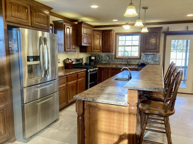 kitchen featuring sink, ornamental molding, a center island with sink, and appliances with stainless steel finishes