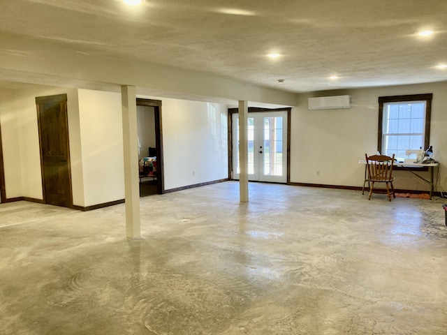 basement with a wall unit AC, plenty of natural light, and a textured ceiling