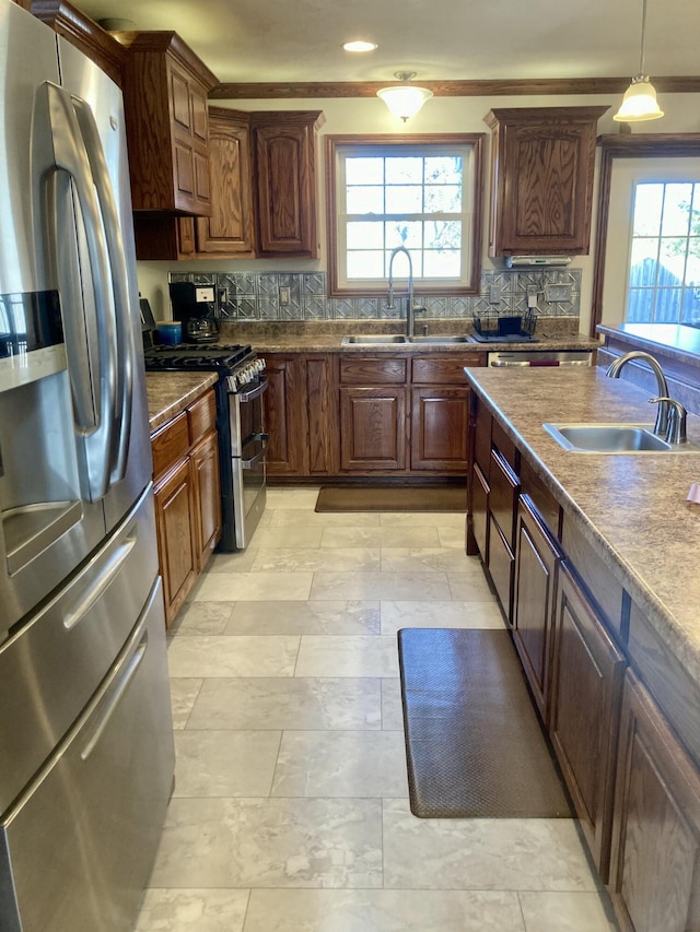 kitchen featuring a wealth of natural light, sink, decorative light fixtures, and appliances with stainless steel finishes