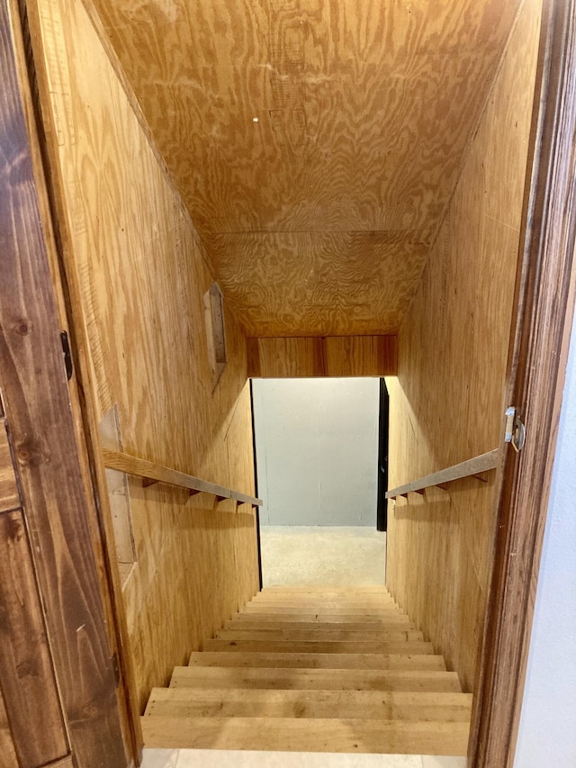 stairway with hardwood / wood-style floors, wood walls, and vaulted ceiling