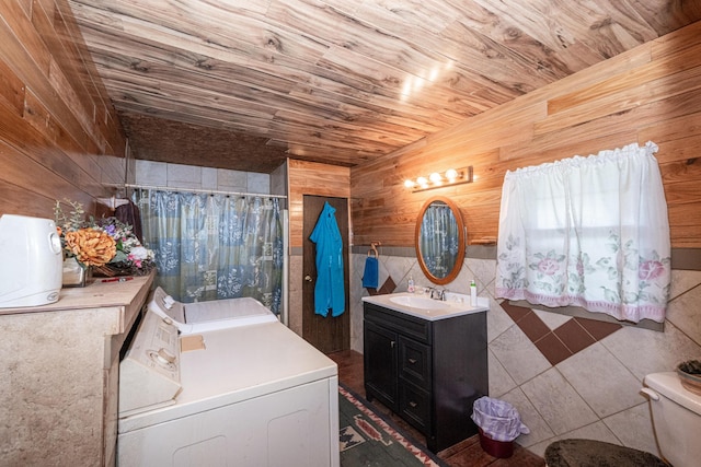 bathroom featuring vanity, wooden walls, toilet, separate washer and dryer, and tile walls