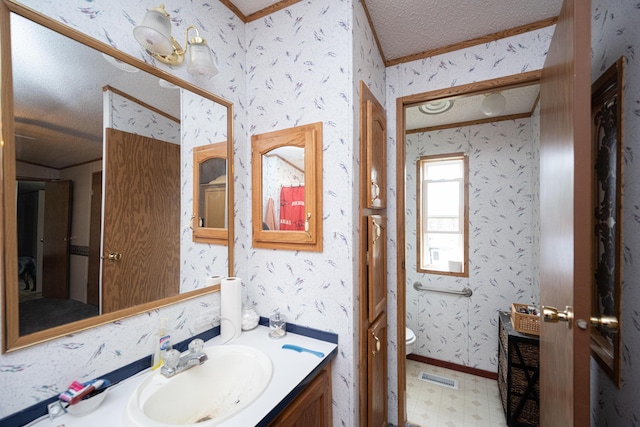 bathroom featuring a textured ceiling, vanity, toilet, and crown molding